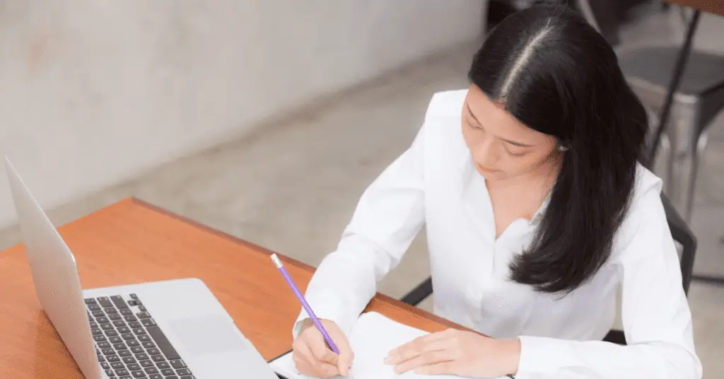 One way to Make Money without Spending Money is freelance writing: lady writing on a note book