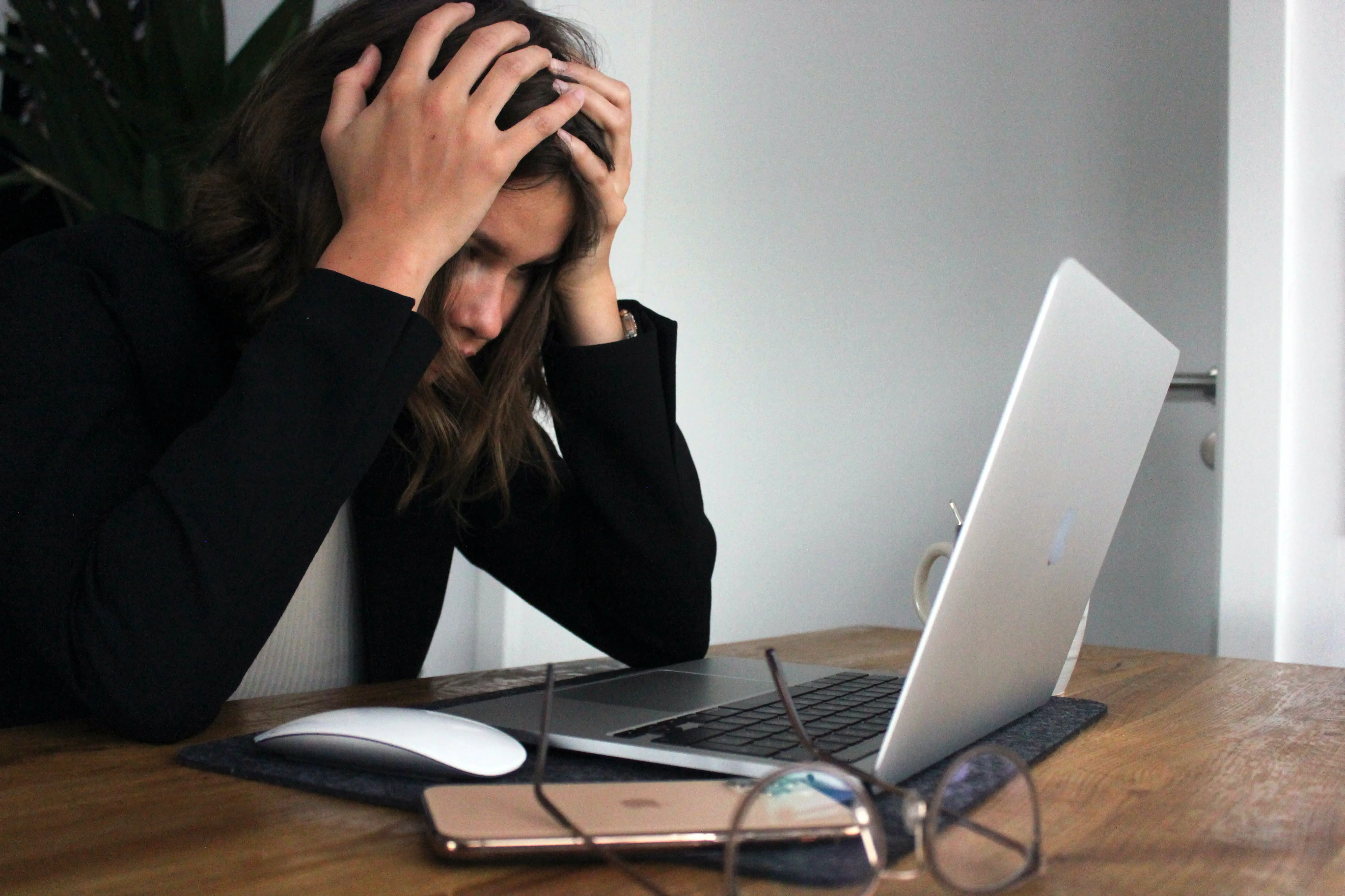 types of entrepreneurial stress - A female entrepreneur held her head in front of her laptop as she appeared stressed