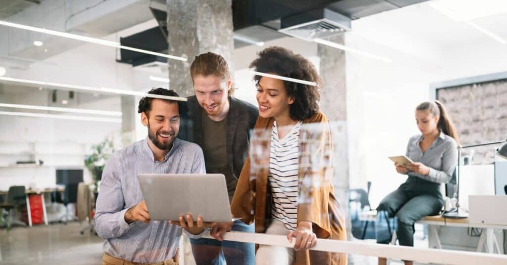 A group of people brainstorming online store promotion ideas in an office while looking at a laptop.