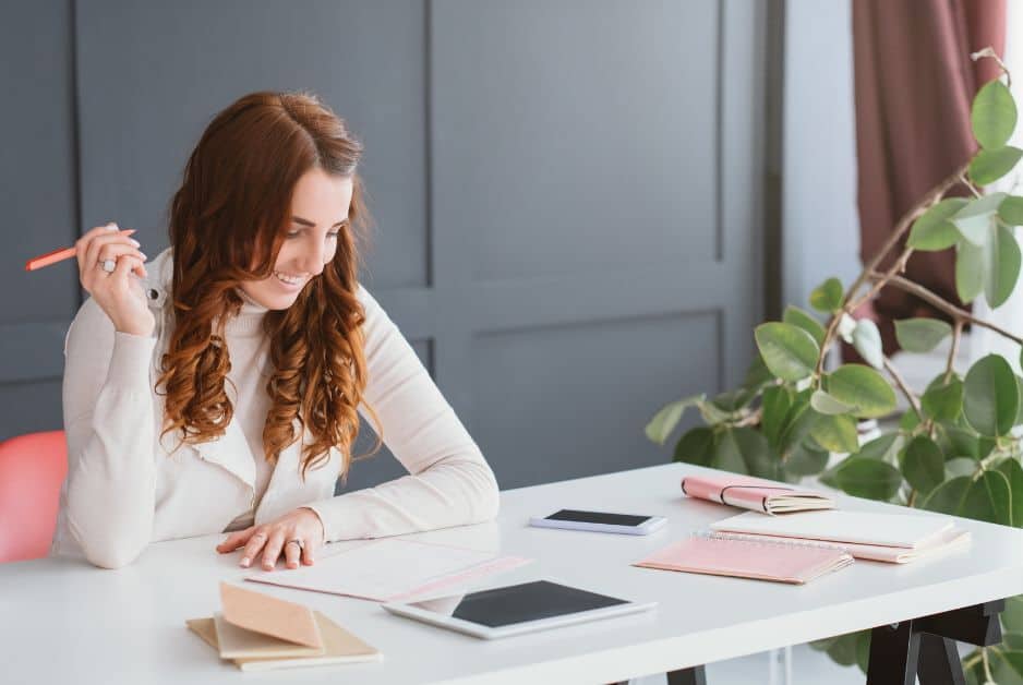 things to know before starting an online business - A woman preparing a marketing plan for her online business, sitting at a desk with a pen and notebook.