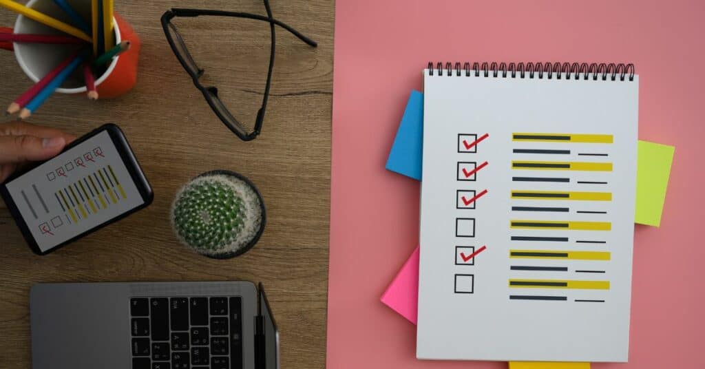 A notebook with a to-do checklist next to a laptop at work.